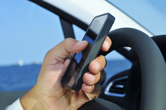 man using a smartphone while driving a car